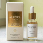 Astuccio per skincare in cartoncino soft touch con logo in foil oro accanto a un flacone di siero